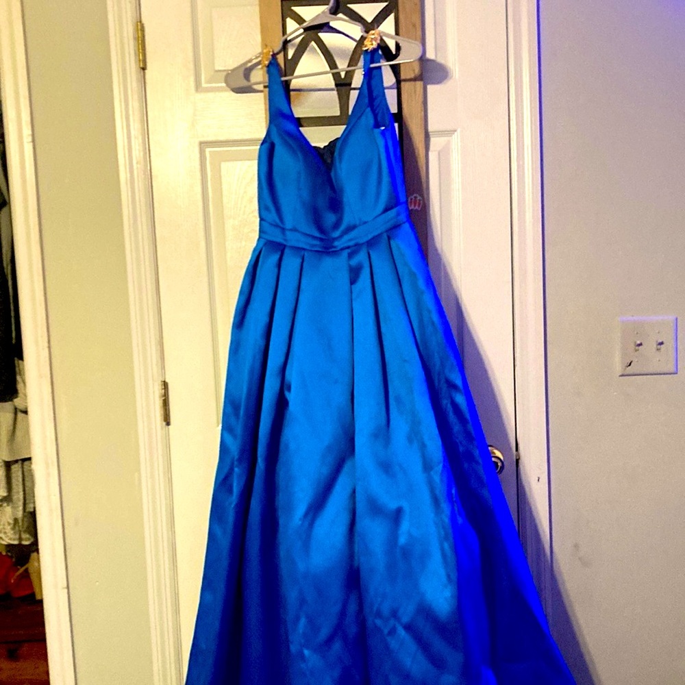 A long blue dress that has pockets and golden leaves on the straps
